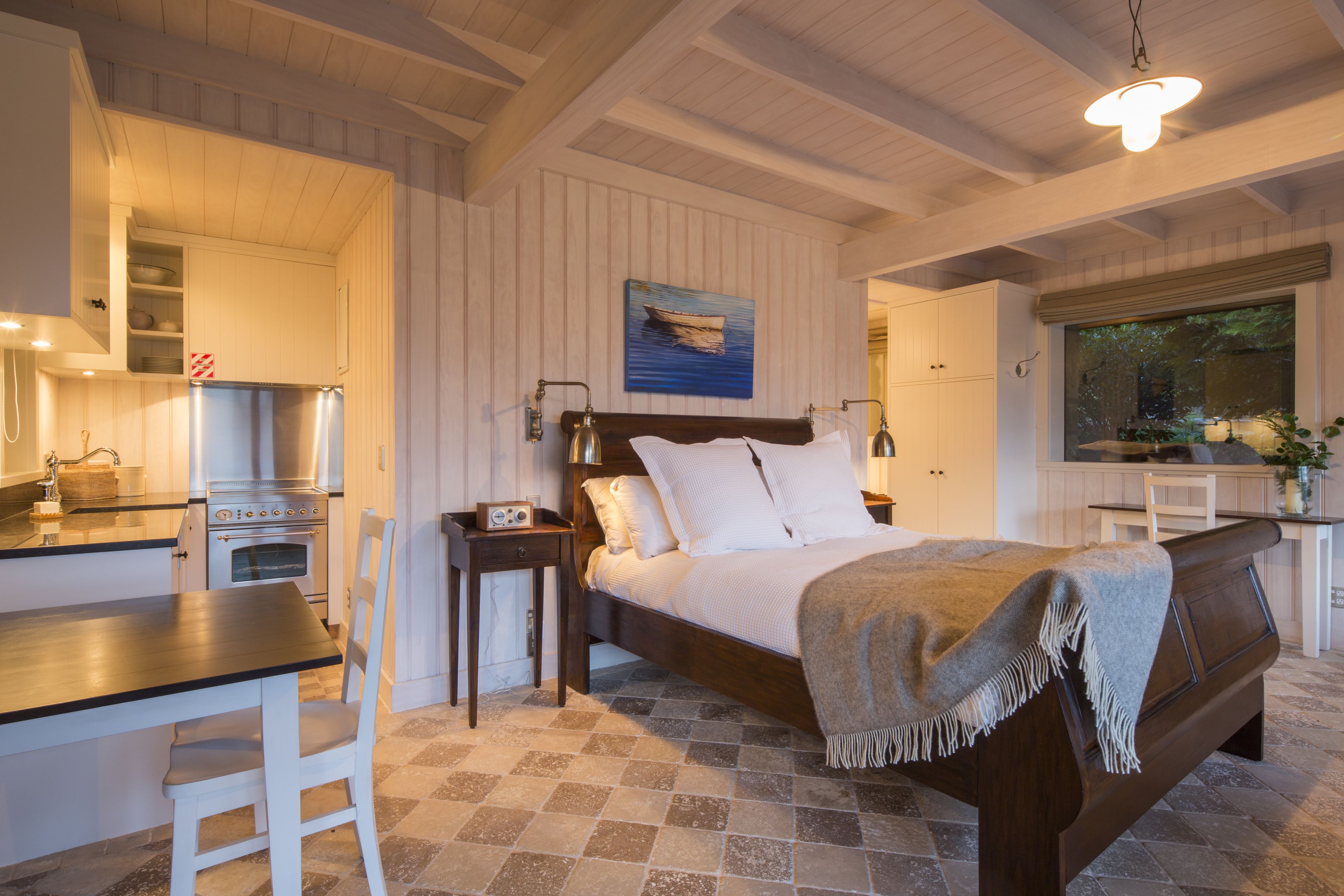 Ein Schlafzimmer mit Bett, Nachttisch und Blick zur Küche.