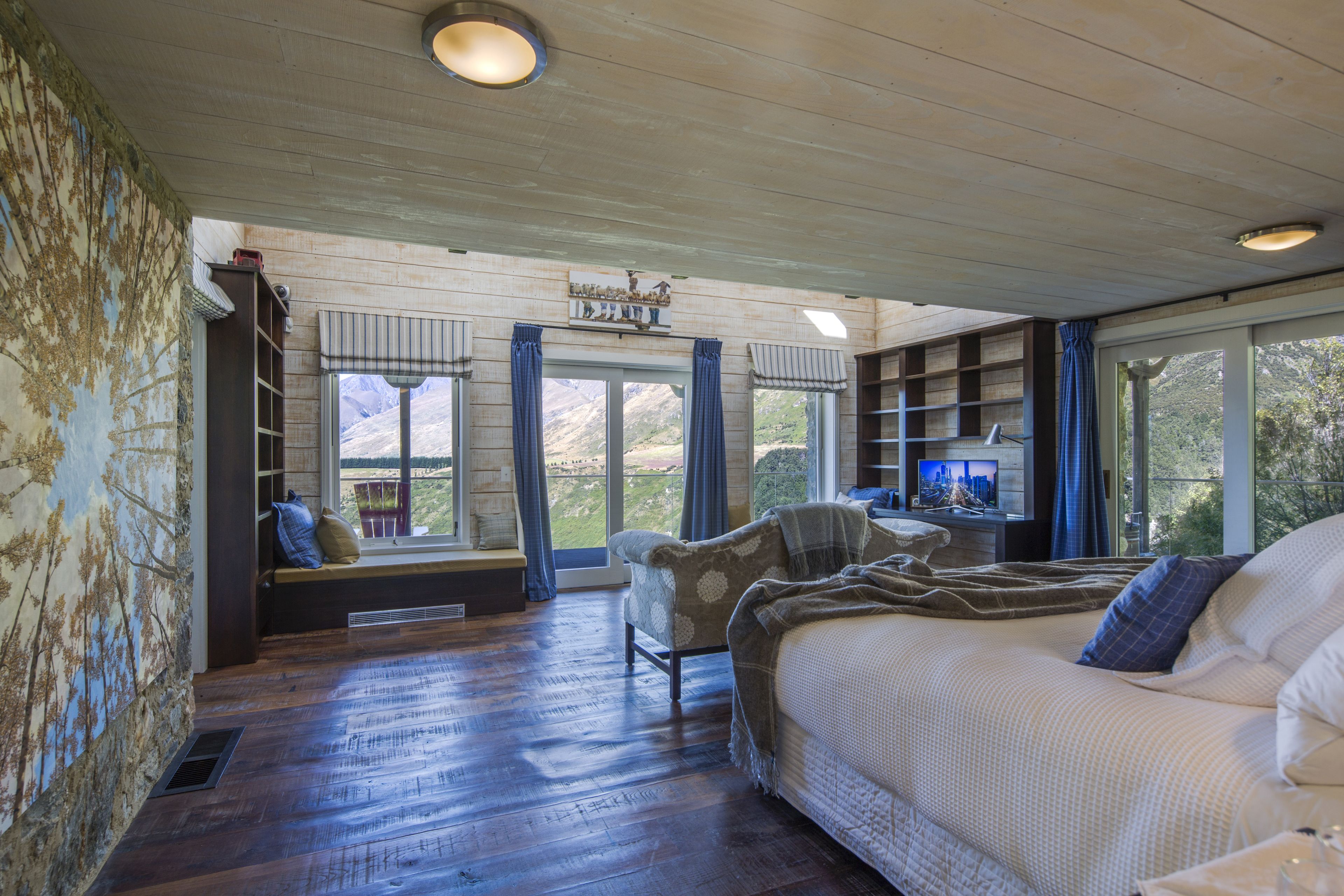 A bedroom with a large bed, a chair, a desk, and a window with curtains.
