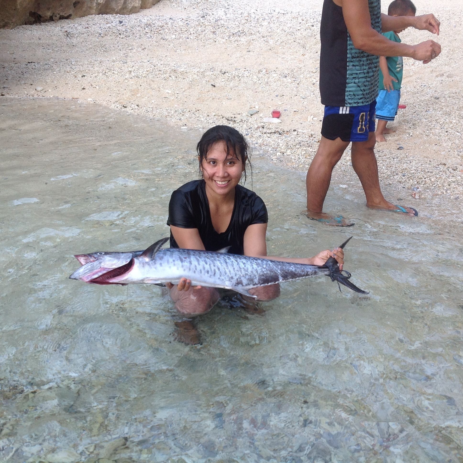A person holding a large fish in shallow water.