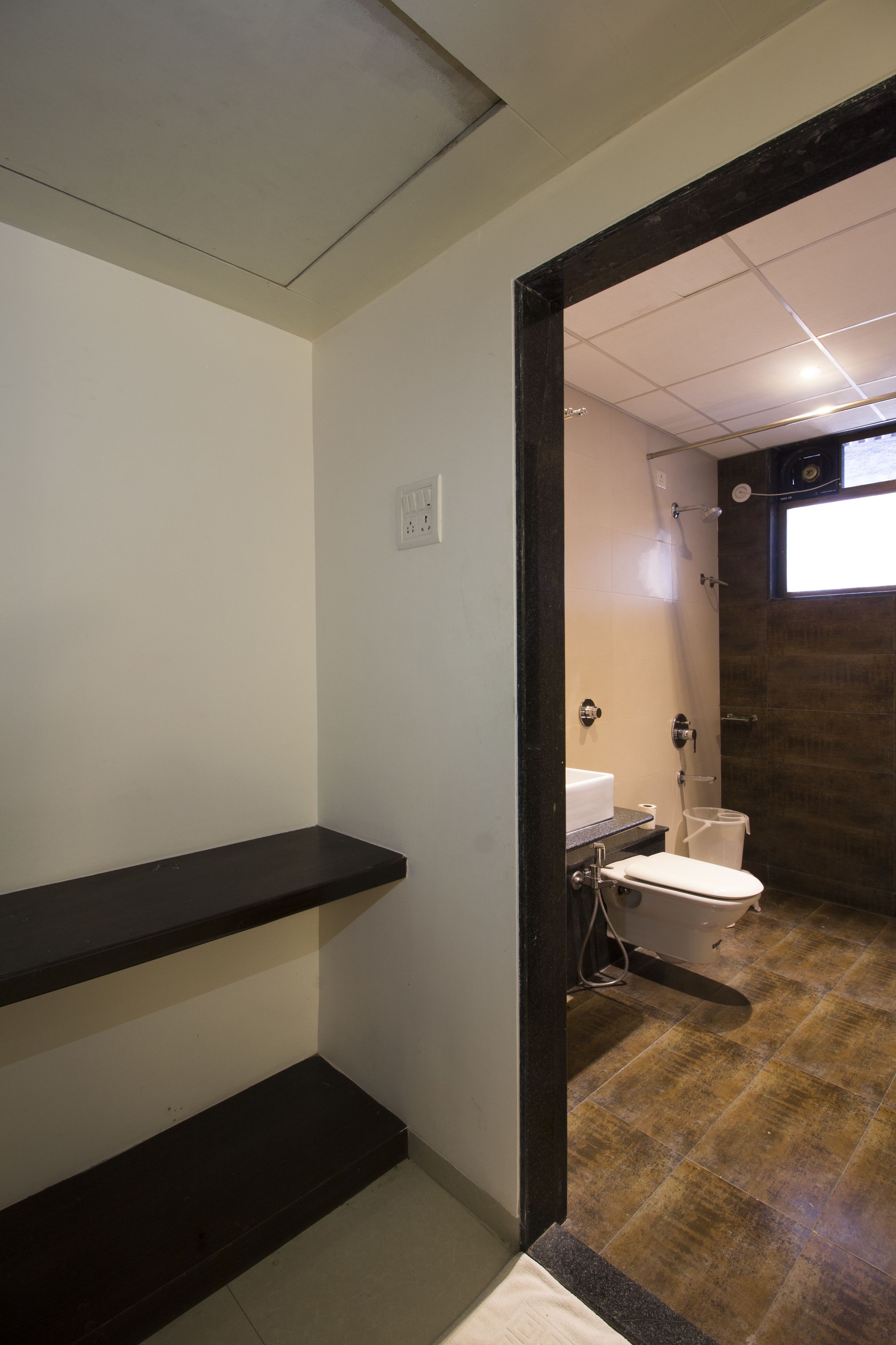 A bathroom with a toilet, shower, and a shelf.