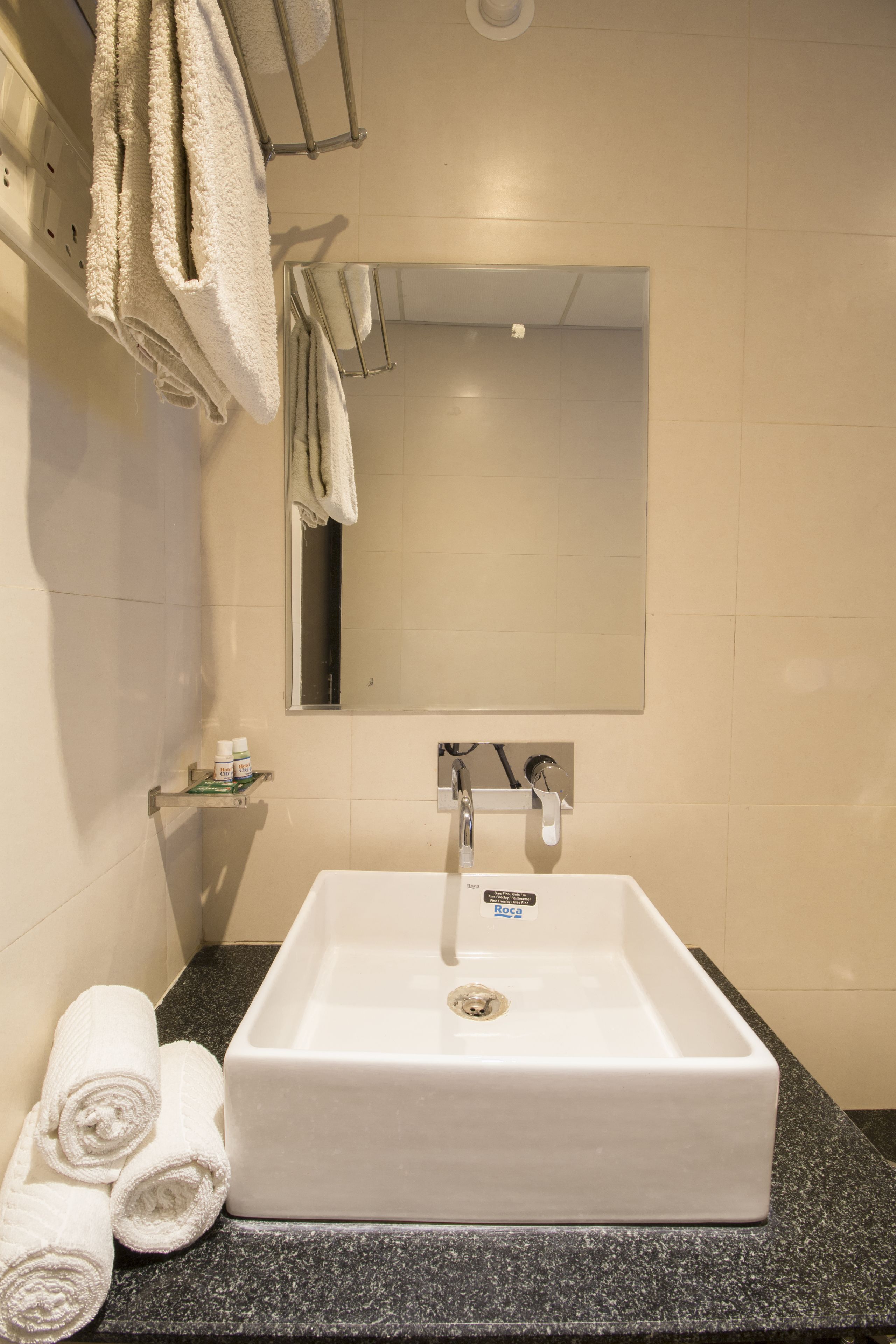 Une salle de bain avec un lavabo blanc, un miroir et des serviettes posées sur le comptoir.