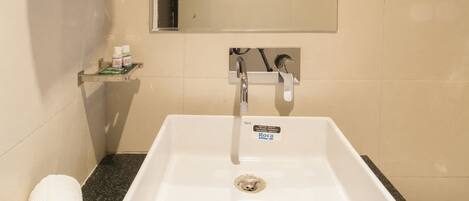 Une salle de bain avec un lavabo blanc, un miroir et des serviettes posées sur le comptoir.
