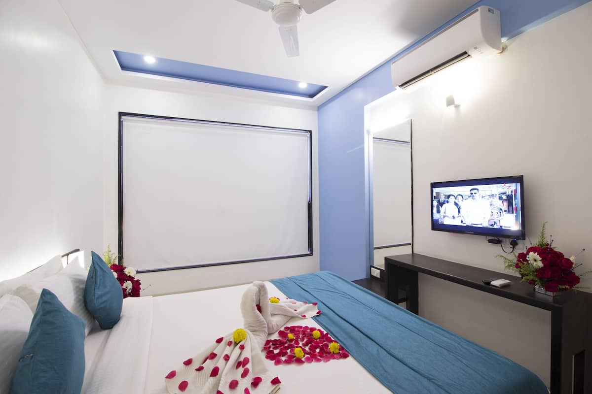 A hotel room with a bed, a TV, a desk, and a mirror.