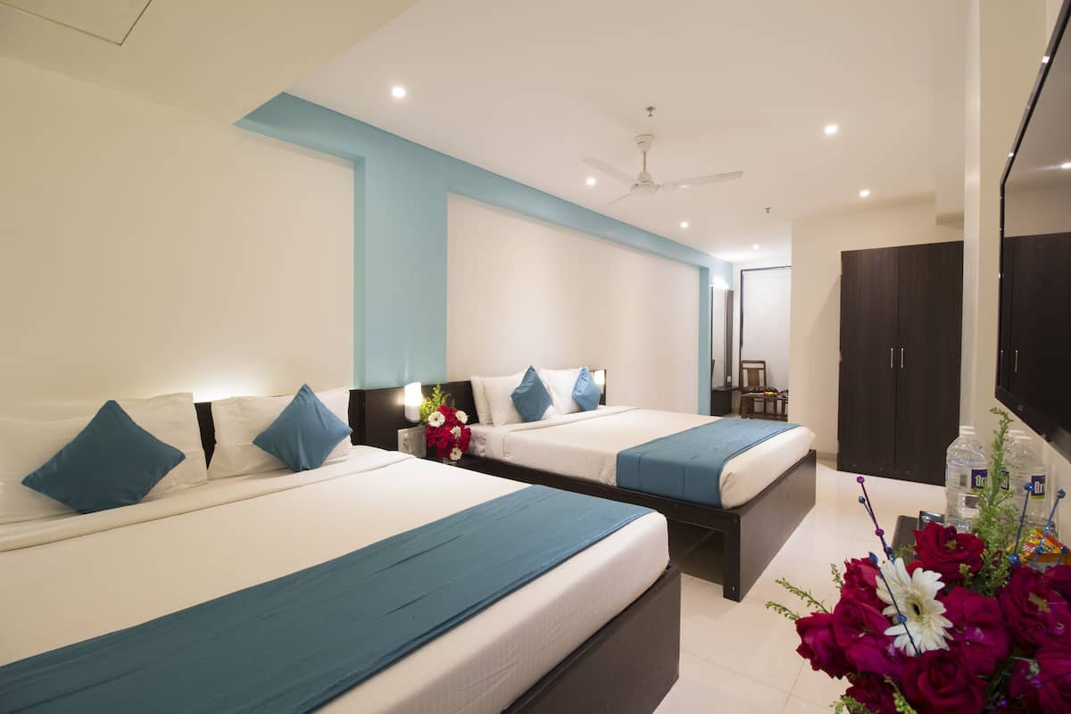 A hotel room with two beds, a ceiling fan, a flat-screen TV, and a large mirror.