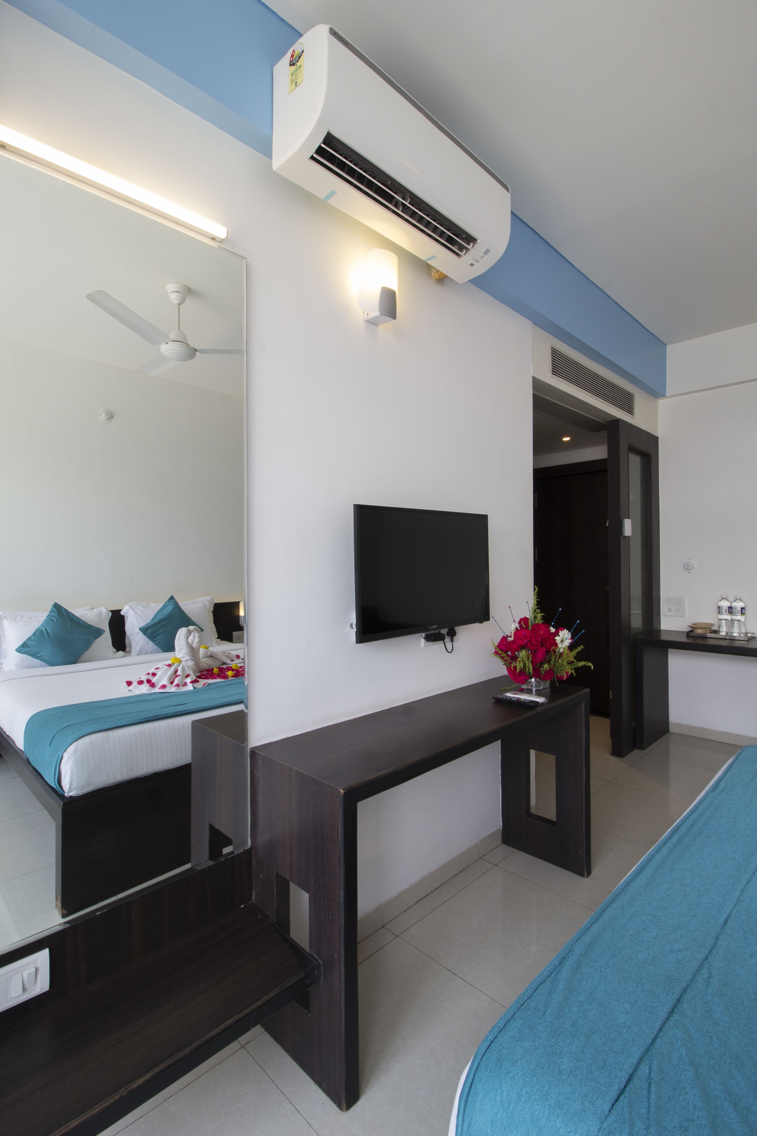Una habitación de hotel con cama, televisor, escritorio y kitchenette.