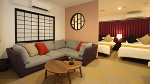 Ein Hotelzimmer mit einer Couch, einem kleinen Holztisch, zwei Betten und einer Wanddekoration.