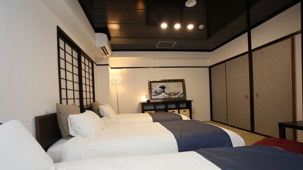 Ein Hotelzimmer mit zwei Betten, einem großen Fenster mit Blick, einem Bild an der Wand und einer traditionellen japanischen Schiebetür.