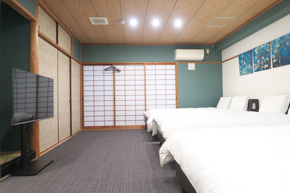 A hotel room with a bed, a TV, a wardrobe, and a sliding door.