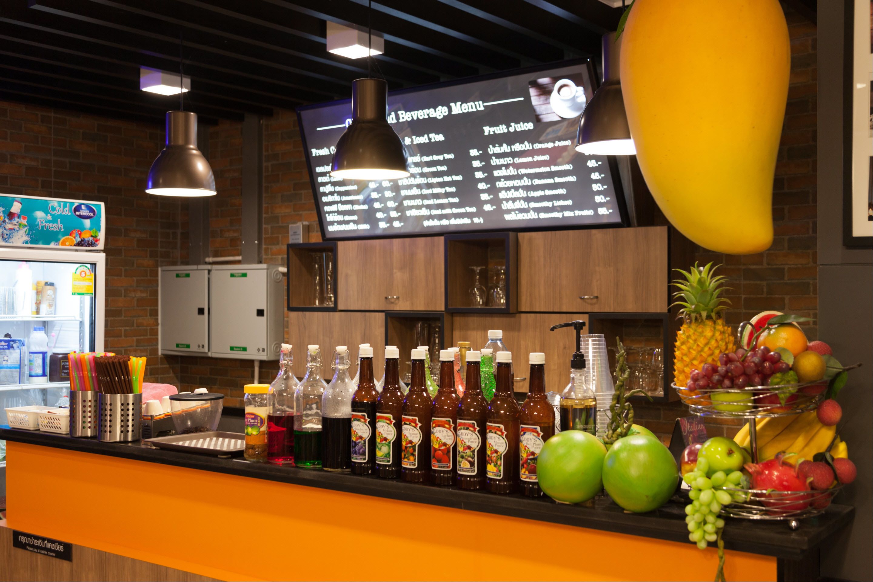 A beverage bar with a menu, various drinks, and fresh fruits.
