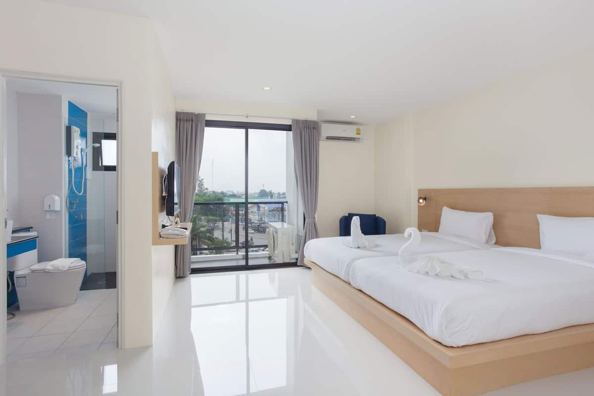 Quarto de hotel com uma cama grande, televisão, varanda com vista e banheiro com vaso sanitário e chuveiro.