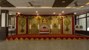 A stage with a red carpet, golden pillars, and floral decorations. - Hotel Sownthariyam (Palani)