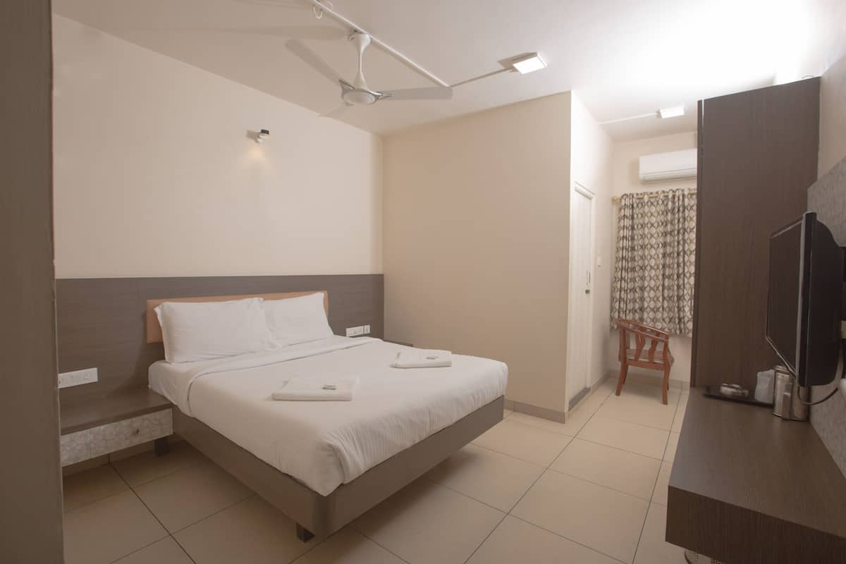 A hotel room with a bed, a desk, a chair, and a television.