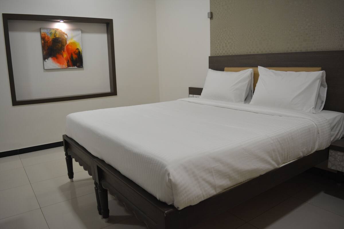 A neatly made bed in a hotel room with a framed artwork on the wall.