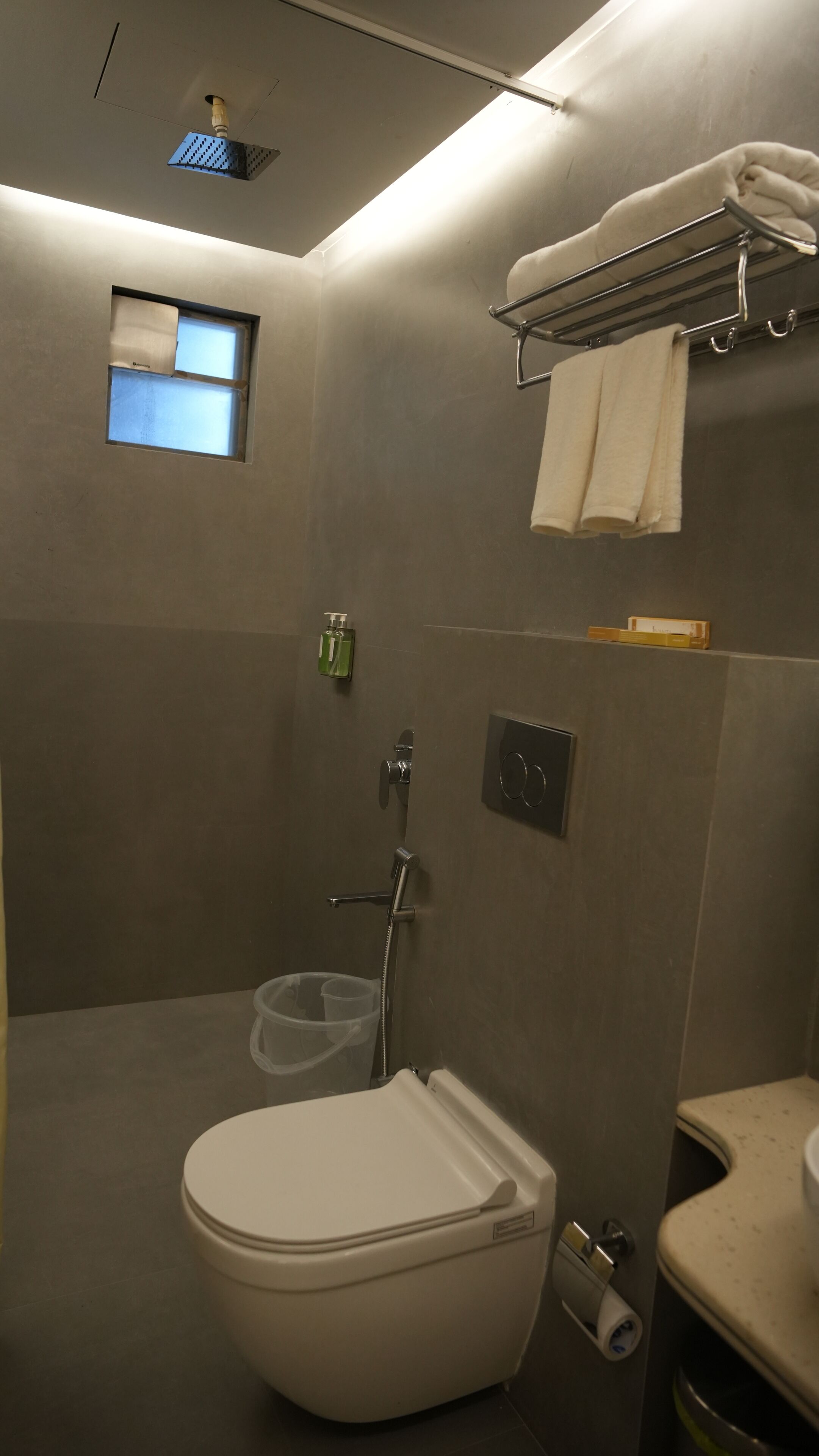 A modern bathroom with a toilet, shower, and towel rack.