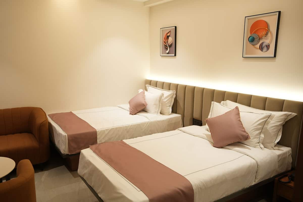Ein Hotelzimmer mit zwei Betten, einem Schlafsofa und einem kleinen Tisch.