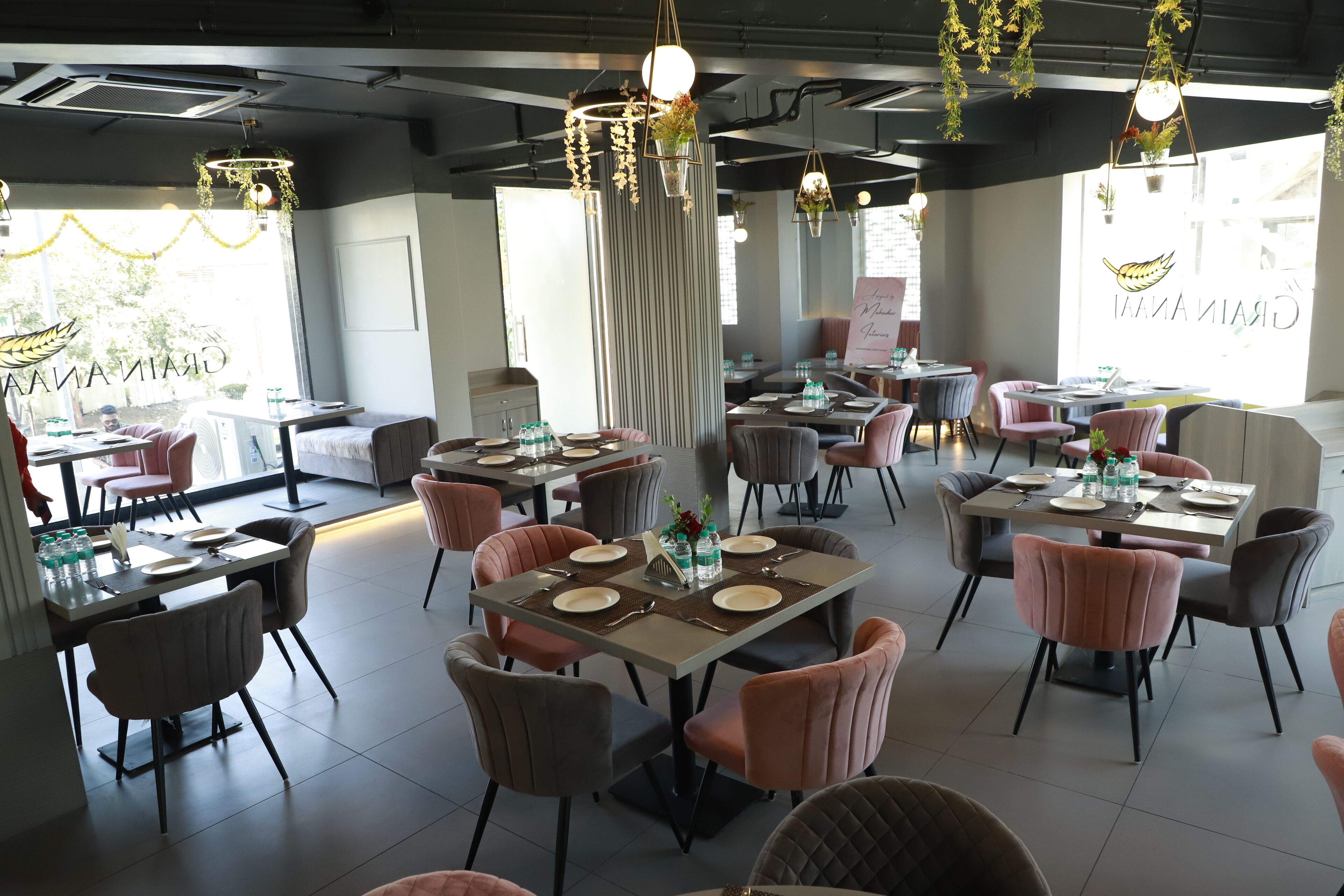 A restaurant with multiple tables and chairs, some with floral centerpieces.