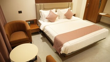 Una habitación de hotel con cama, una silla, una mesita y una mesita de noche.