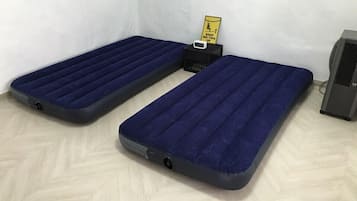 Two blue mattresses with a control panel and a fan in a corner.