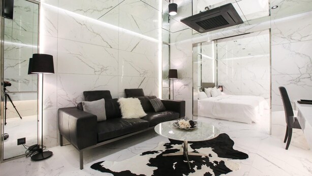 A modern hotel room with a black leather sofa, a round coffee table, a white bed, and a glass shower enclosure. - Hotel Star Premier Yeoksam (Seoul)