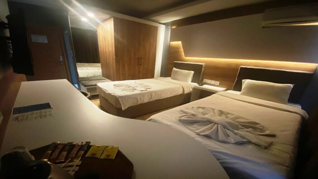 A hotel room with two beds, a desk, and a wardrobe.