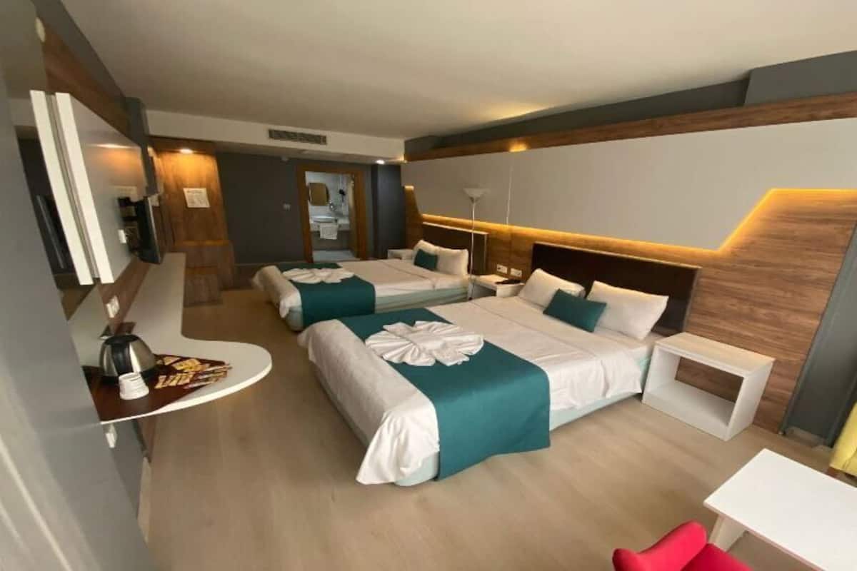 Una habitación de hotel con dos camas, un escritorio, una silla y un televisor.
