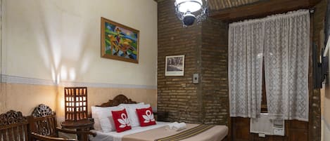 A room with a bed, wooden furniture, a painting, a chandelier, and a window with curtains.