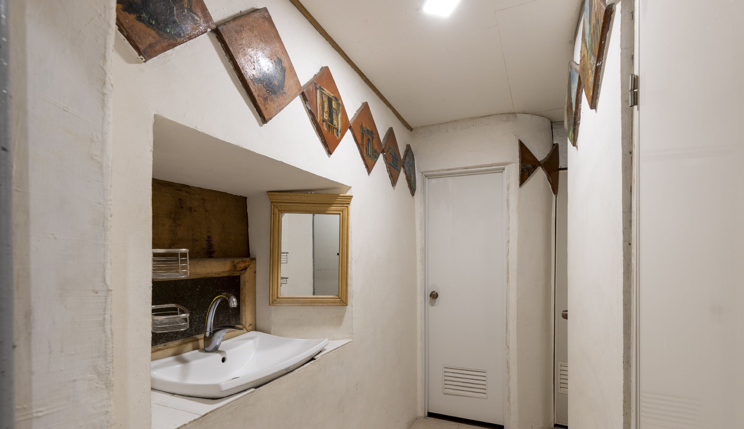A bathroom with a sink, mirror, and a door.