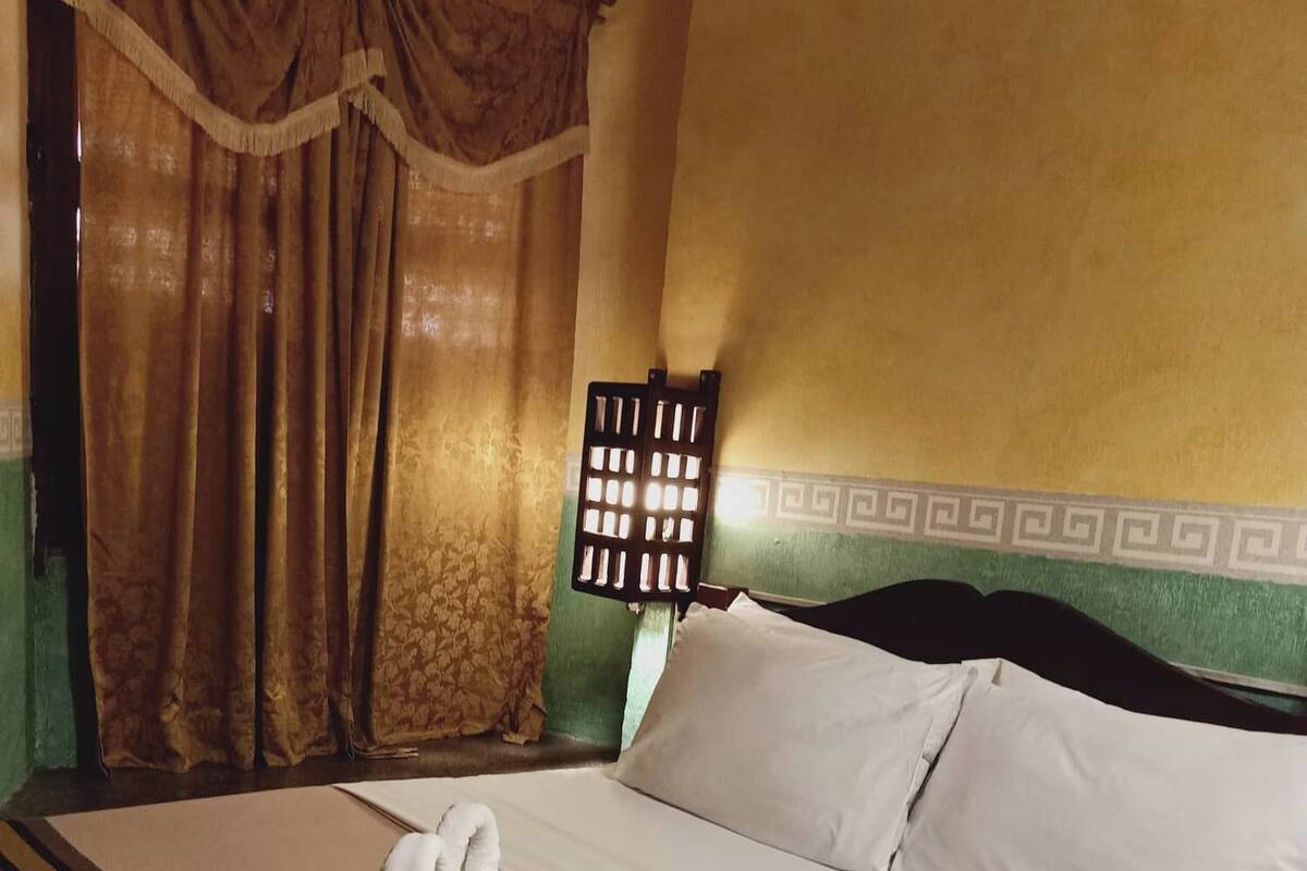 A neatly made bed with a white towel, a striped blanket, and a pillow.
