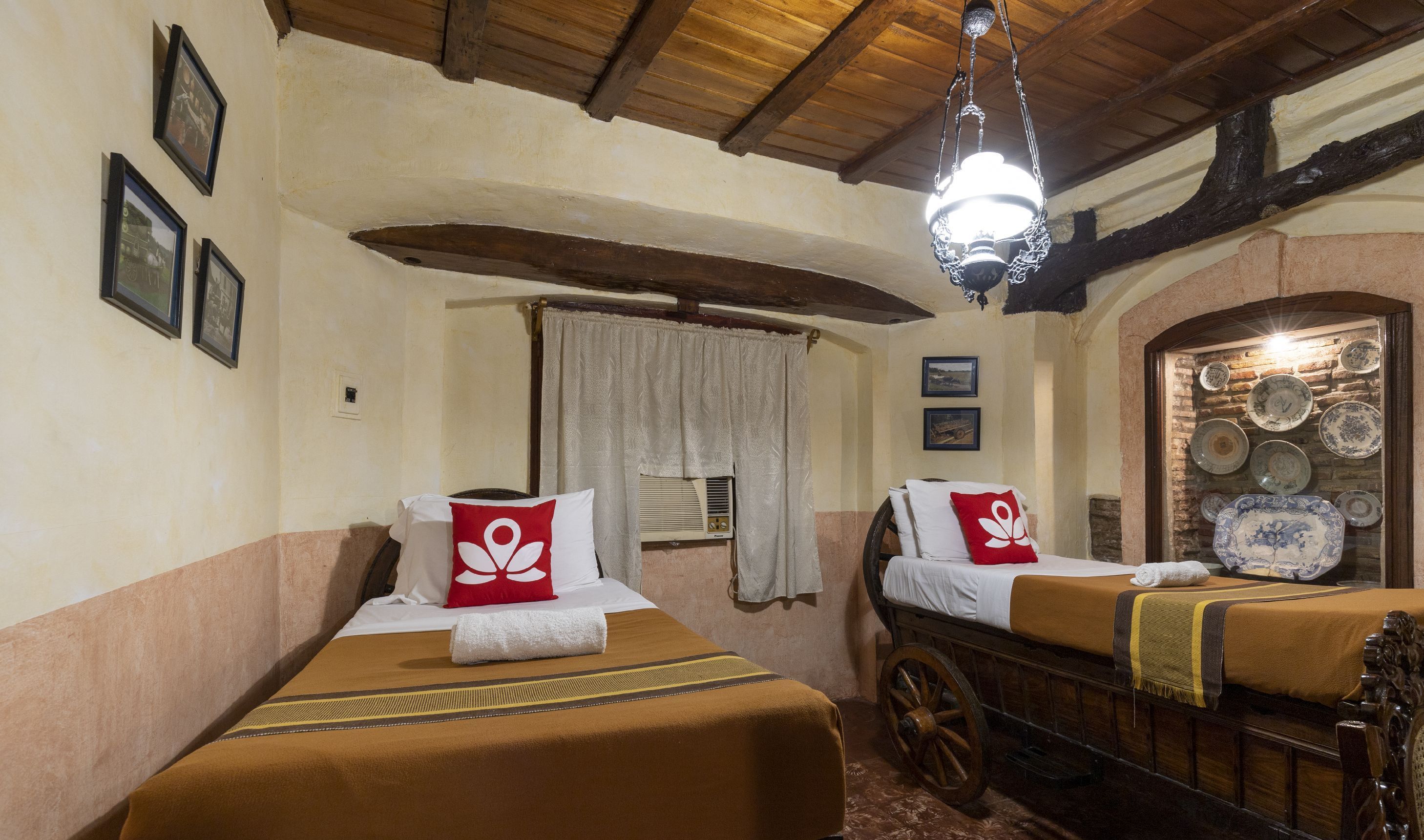 A traditional room with two beds, a wooden bench, and a wall of decorative plates.