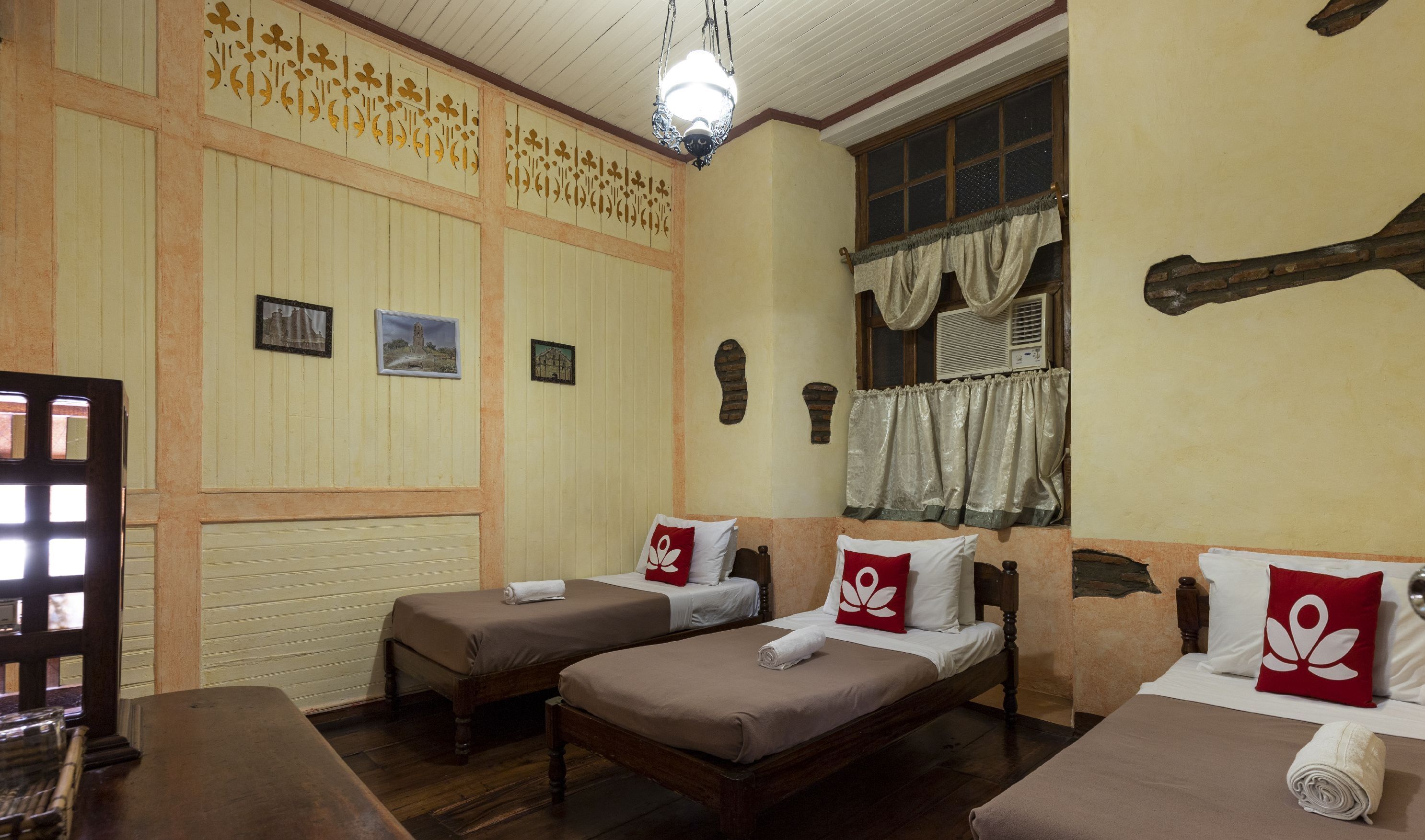 Una habitación tradicional con dos camas individuales, pisos de madera y un ventanal con cortinas.