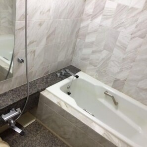 A bathroom with a bathtub, marble tiles, a granite countertop, and a mirror. - Hotel Hamatsu (Koriyama)