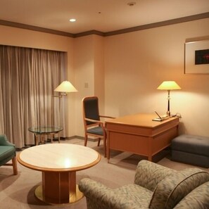 A hotel room with a round table, a desk, two chairs, a sofa, a glass table, and two lamps. - Hotel Hamatsu (Koriyama)