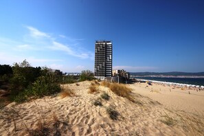 A coastal hotel with a modern design, situated on a sandy beach with a view of the sea. - Menada Dune Residence Apartments (Sunny Beach)
