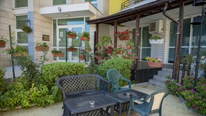 An outdoor patio with a table and chairs, surrounded by potted plants and a fence. - Menada Sea Regal Apartments (Sunny Beach)