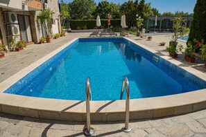 A rectangular swimming pool with clear blue water, surrounded by a stone deck and potted plants. - Menada Sea Regal Apartments (Sunny Beach)