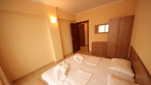 A bedroom with a bed, a wooden wardrobe, and a nightstand. - Menada Sea Regal Apartments (Sunny Beach)