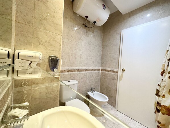 Un baño con inodoro, bidé y secador de manos.