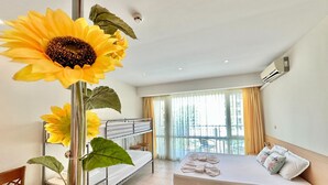 Et hotelværelse med køjeseng, sovesofa, stort vindue med gardiner og en solsikke-dekoration.