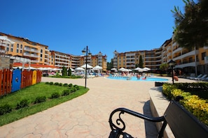 A hotel courtyard with a swimming pool, outdoor seating, and a well-maintained garden. - Menada Royal Sun Apartments (Sunny Beach)