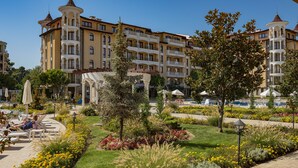A hotel with multiple balconies, a pool area, and a landscaped garden. - Menada Royal Sun Apartments (Sunny Beach)