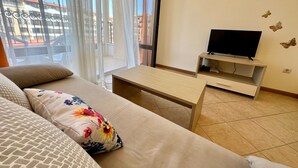 A modern living room with a sofa, a coffee table, and a TV on a stand. - Menada Royal Sun Apartments (Sunny Beach)