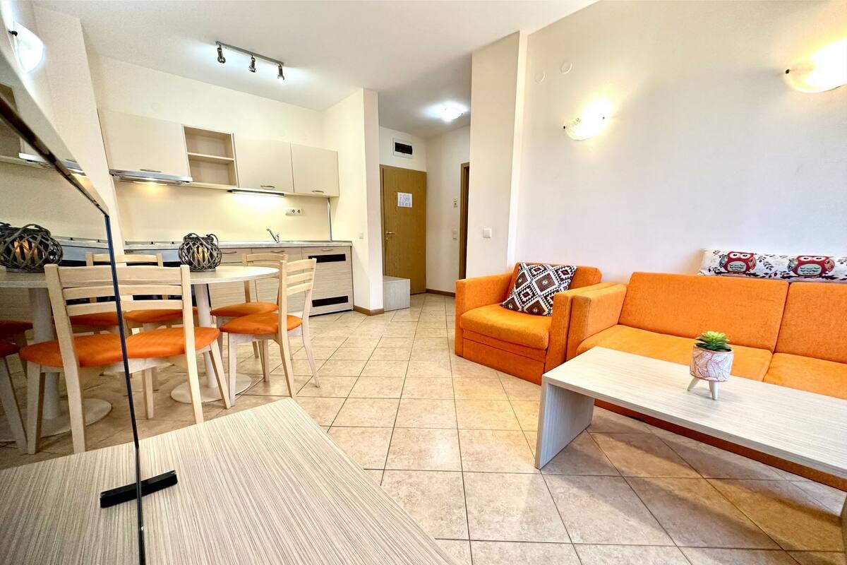 A modern living room with a sofa, a coffee table, and a dining area with chairs and a table.