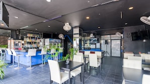 Un restaurante moderno con zona de bar, sillas y mesas blancas.