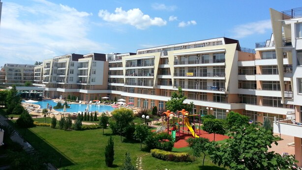 A multi-story hotel with a swimming pool and children's play area. - Menada Grand Kamelia Apartments (Sunny Beach)