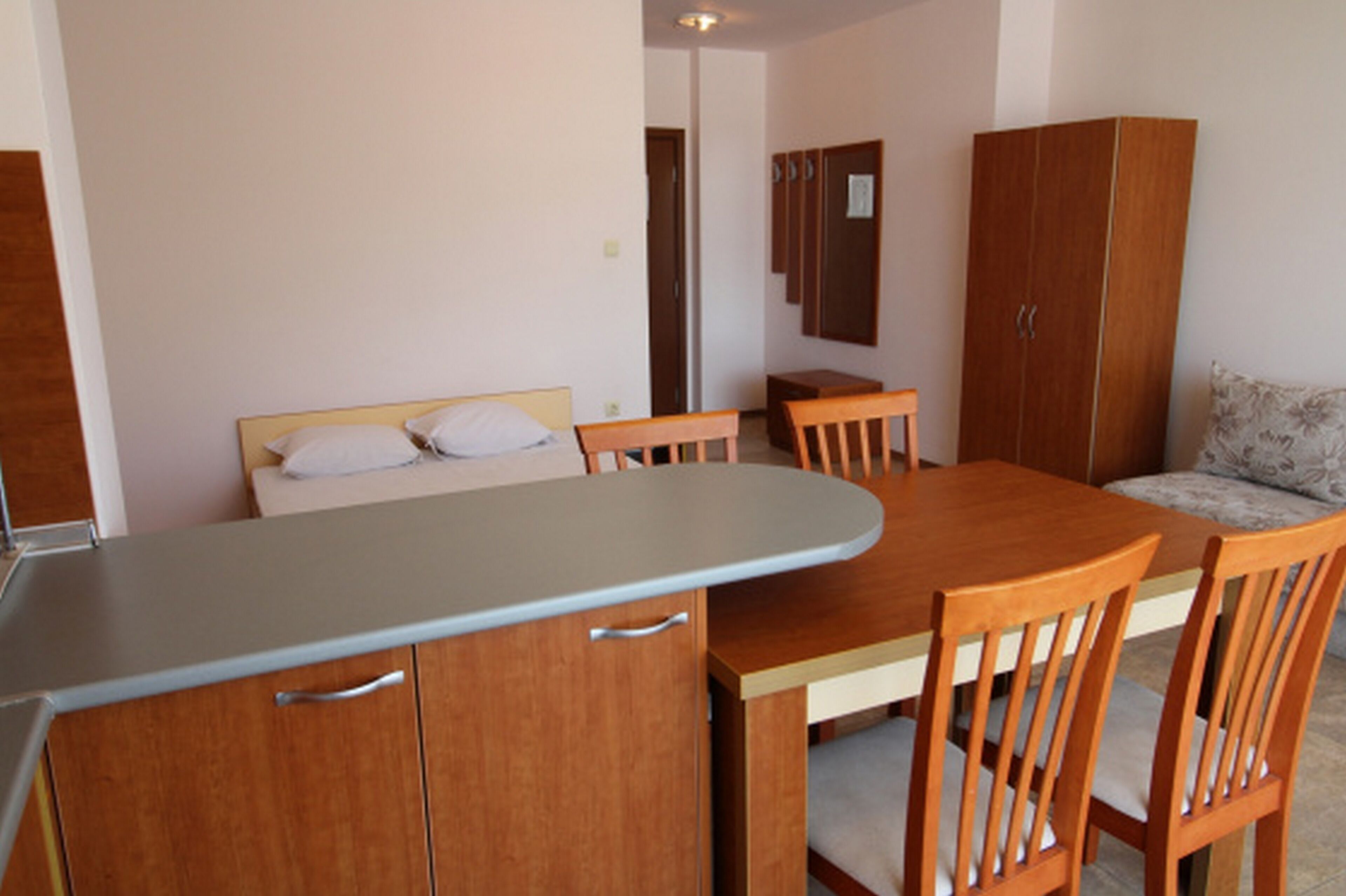A compact room with a bed, a small table with chairs, and a wardrobe.