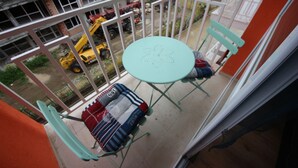 Un balcone con tavolo e sedie, affaccia su un cantiere con veicoli.