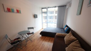 Un ambiente compatto con un letto, un tavolino e una sedia.