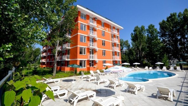 Un hotel a più piani con piscina, area salotto all'aperto e rigogliosa vegetazione.