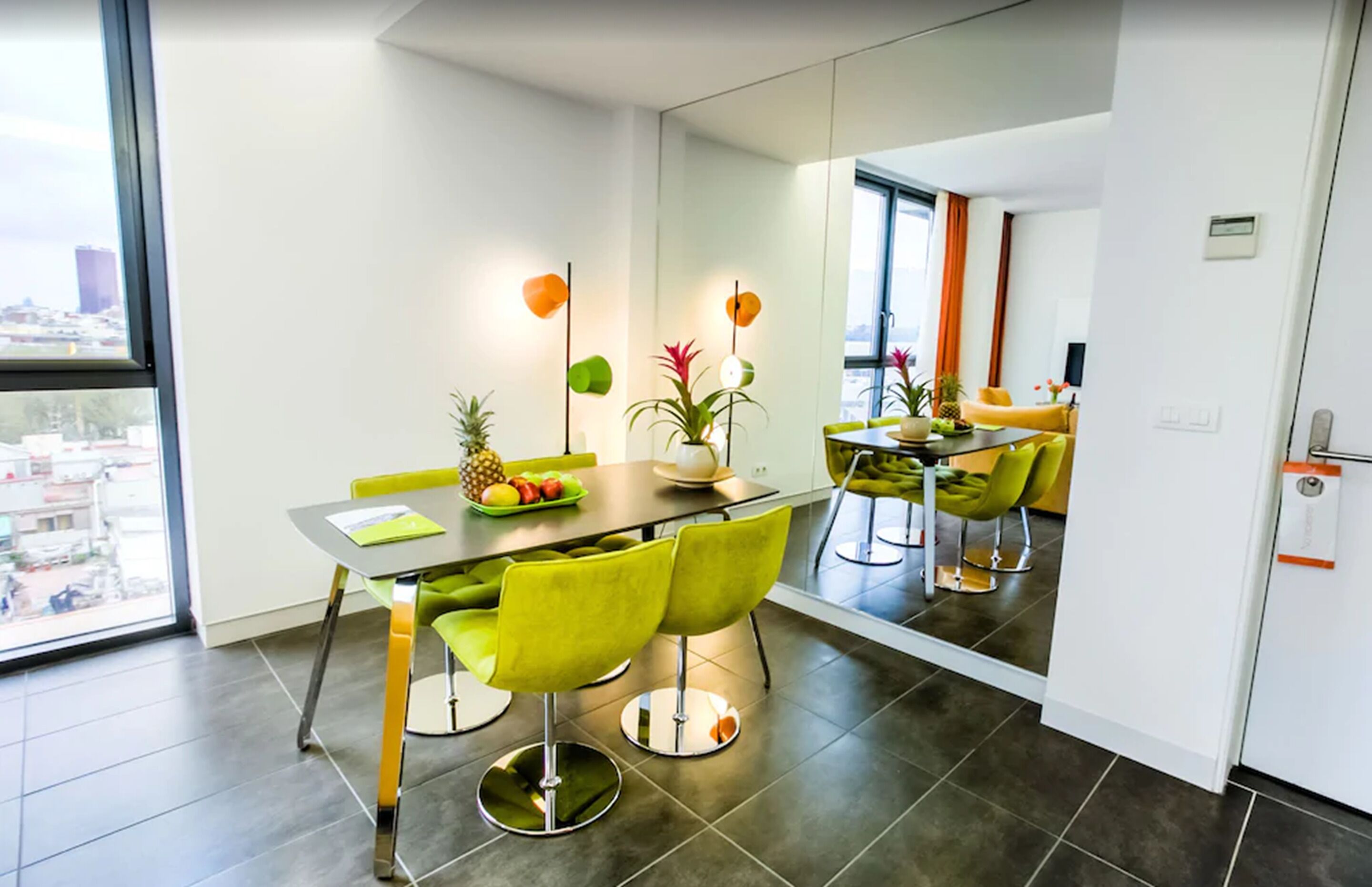 A modern dining area with a table, chairs, and a view of the city through large windows.