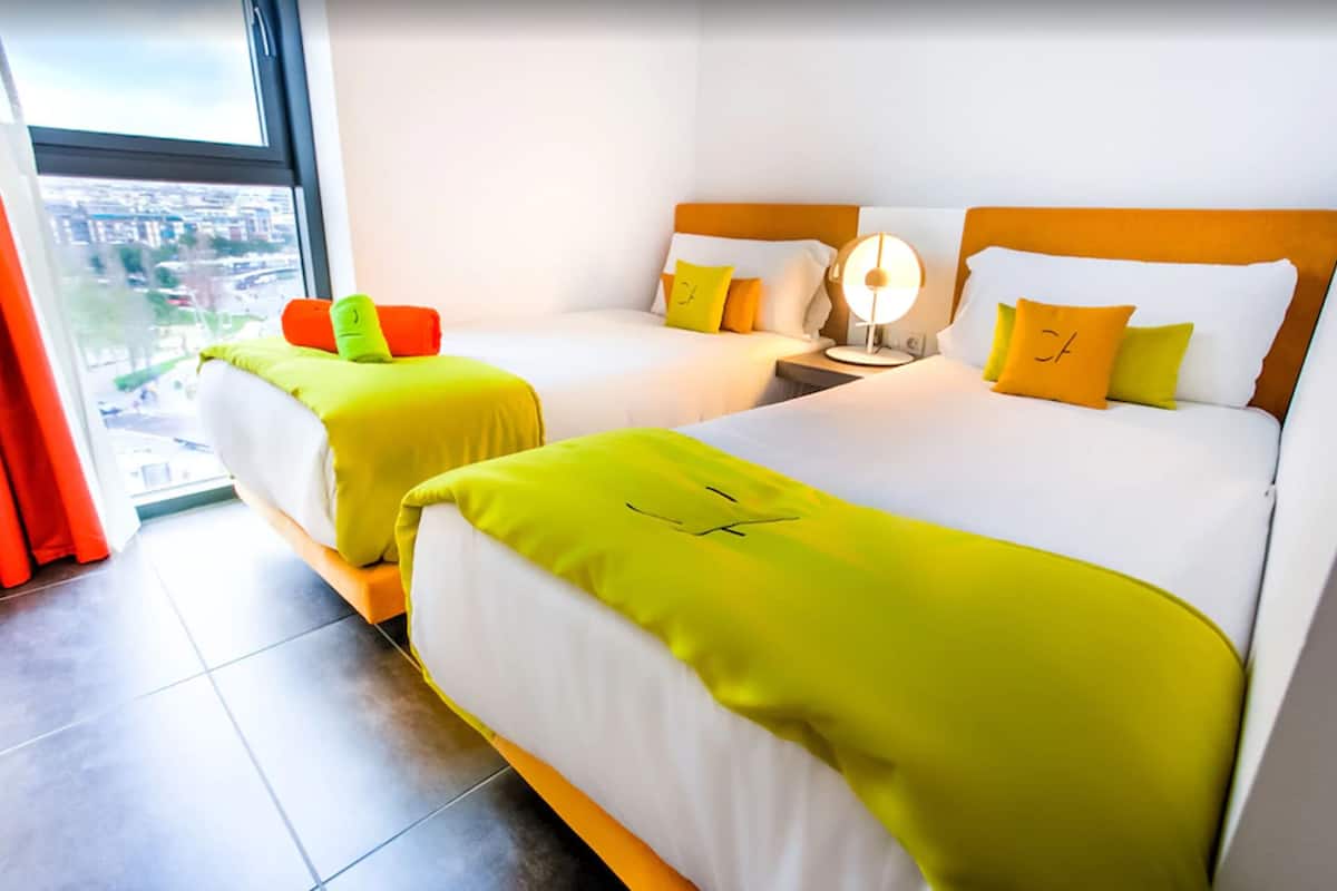 A hotel room with two beds, a city view, and a modern design.